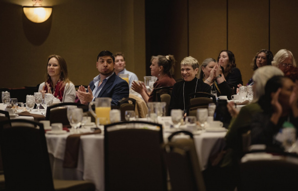 A group of people seated at round tables applauding