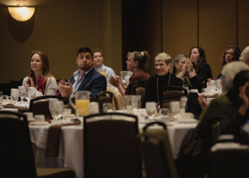 A group of people seated at round tables applauding